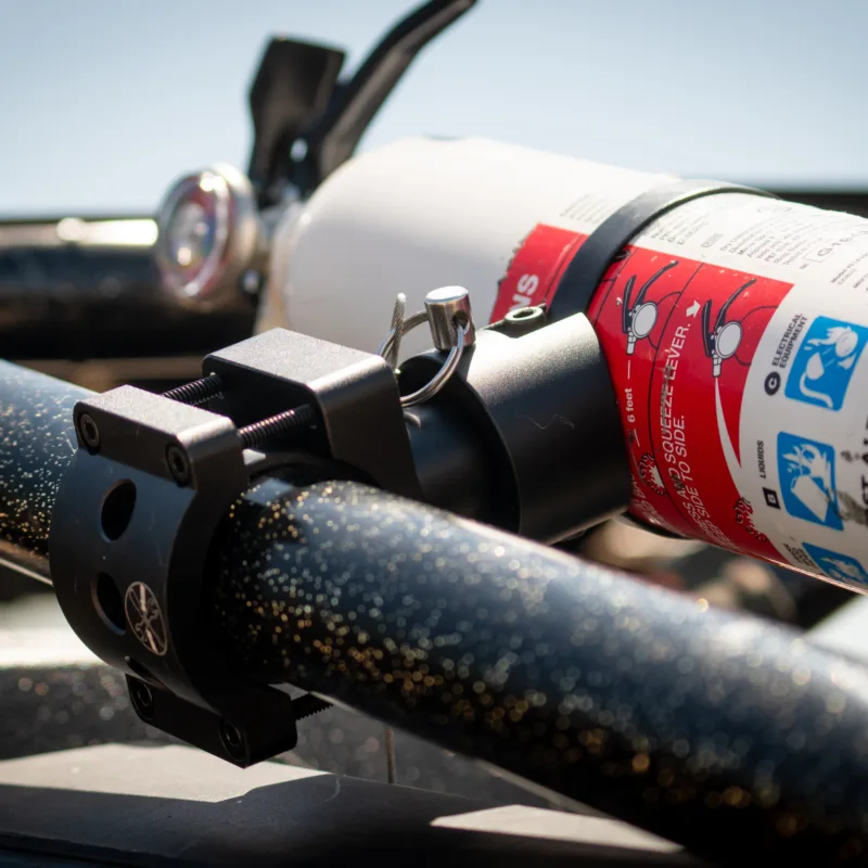 Quick release fire extinguisher mount with First Alert MARINE1 on a Polaris RZR Pro R roll bar, featuring 360° rotation and billet aluminum design.