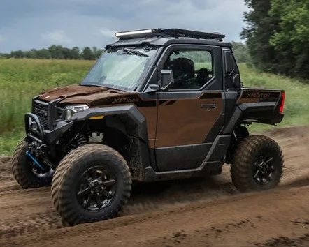 Two-seat Polaris XPEDITION utility model driving on a dirt road with enclosed cab and cargo bed